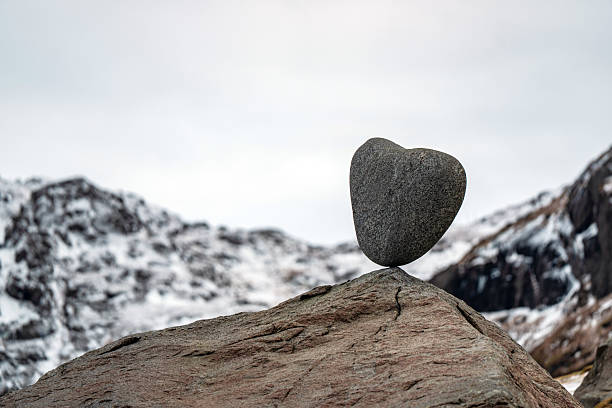 Heart shaped stone balancing creating a symbol of love, balance, and stability in winter