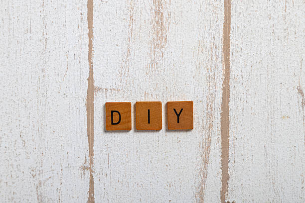 DIY spelled with wooden letter tiles on a white rustic wooden surface. Minimal flat lay with copy space, creative concept for handmade projects, crafts, branding or small business themes.