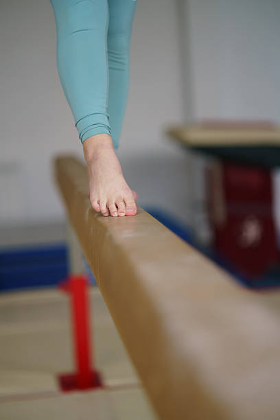 Athlete's bare foot precise on balance beam, showing focus and training.