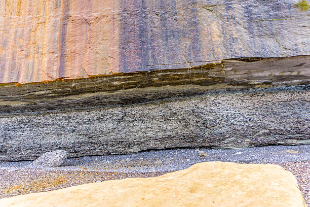 A rock wall with a brown and gray color. The wall is made of stone and has a rough texture