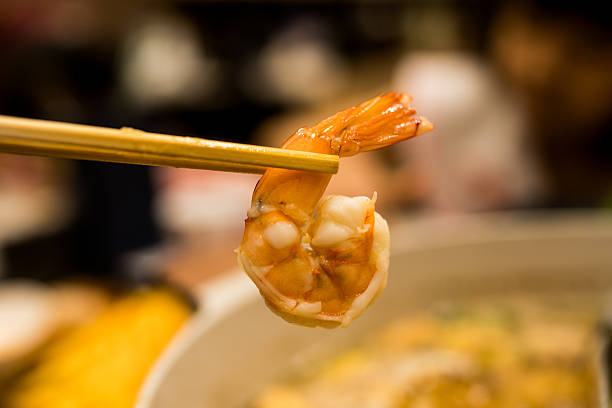 Hand holding chopsticks with shrimp, sukiyaki