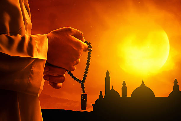 Muslim man hand holding rosary beads at sunset, eid adha mubarak concept