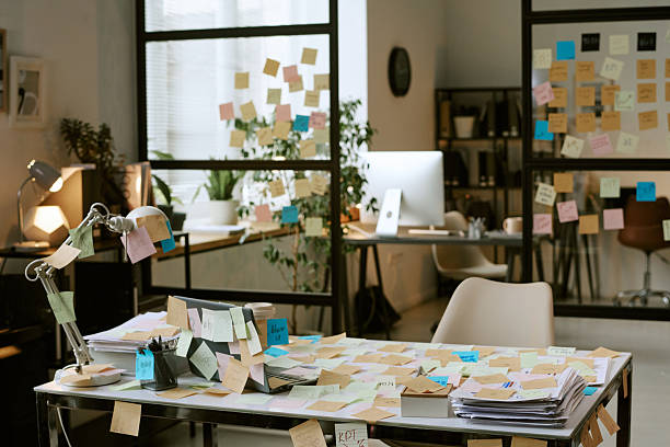 Modern office workspace covered with sticky notes on desk, glass walls, and computer monitor, showing business planning and brainstorming process in professional environment
