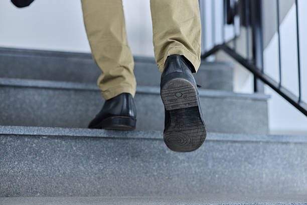 Close up of unrecognizable businessman walking up the stairs in a building.