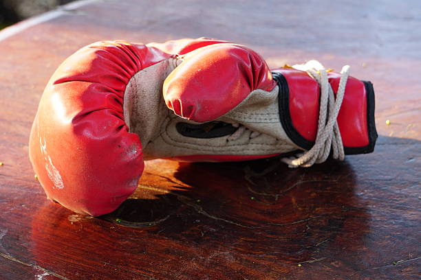 Mature woman in red boxing gloves punches against a brick wall, showcasing strength, fitness and active ageing with focus, energy and determination in an urban workout setting