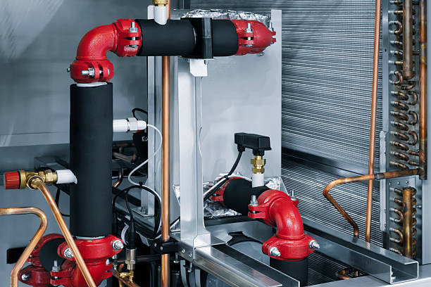Closeup of a heating system valve with a bright orange control knob and piping components