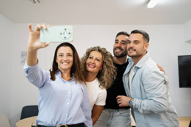 Diverse colleagues taking a group selfie in office