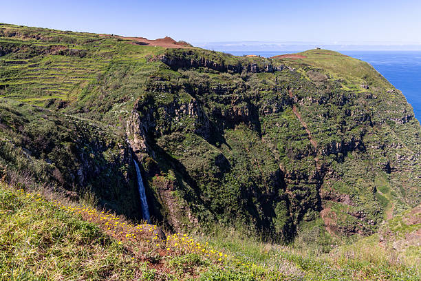 Garganta Funda waterfall cuts through rugged volcanic cliffs at Ponta do Pargo, plunging into deep green gorge above Atlantic coastline of Madeira