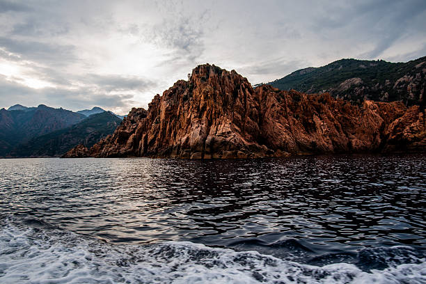 Rocky cliffs rising from the sea along the coast of IleRousse Corsica France. Natural shoreline landscape suitable for travel, tourism, and nature backgrounds.