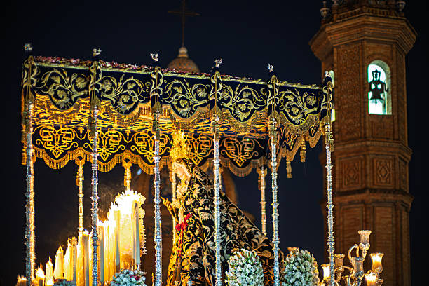 The Virgen de la Estrella palio procession glides past Capilla del Carmen by Triana Bridge on Palm Sunday night, Holy Week, Seville, Andalusia, Spain.