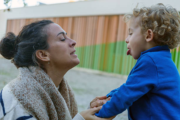 Mother and young son sharing a tender moment outdoors, bonding and making funny faces. Playful family love