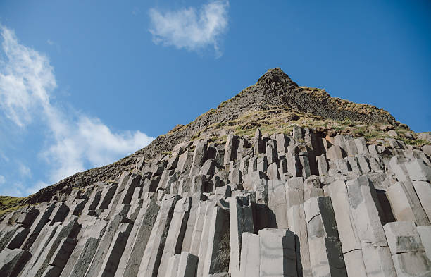 Low angle view of dramatic hexagonal basalt rock formations shaped by ancient lava flows, iconic Icelandic geological landscape featuring rugged textures, natural symmetry and scenic Nordic coastal environment
