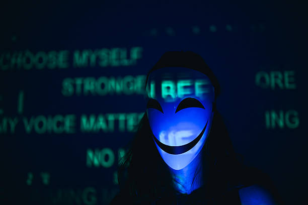 Person wearing a smiling mask illuminated by blue light with green digital typography