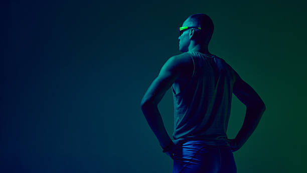 Athlete standing hands on hips in blue-green neon studio lighting. Concept of sports motivation visuals, trainer profile design, fitness challenge promos, athleticwear showcases.