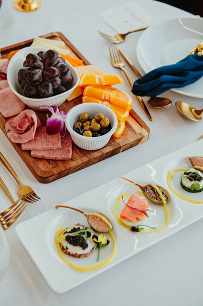 Gourmet food platter elegance. A beautifully arranged gourmet food platter featuring meats, fruits, and delicate appetizers at a dining table.