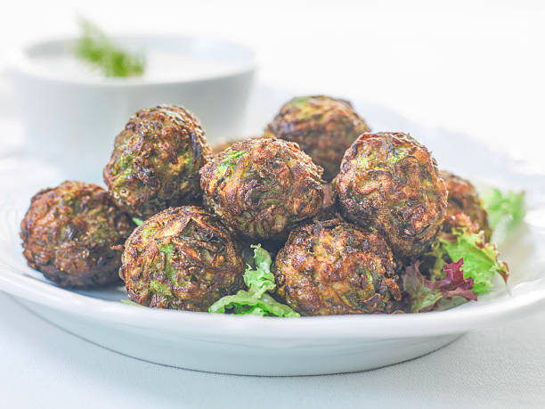 Crispy zucchini balls served on white plate as vegetarian appetizer in restaurant setting