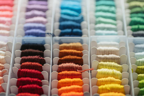 Multicolored sewing threads arranged in storage box, ideal for creative hobby and textile craft concepts.