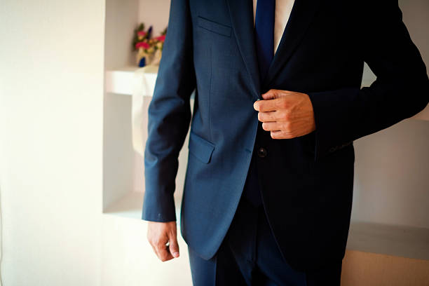 Groom buttoning blue wedding suit jacket. Groom buttoning his elegant dark blue wedding suit before ceremony