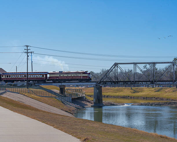 The antique Grapevine Vintage Railroad deisel locomotive crossing the Clearfork River in Trinity Park in Fort Worth, Texas USA