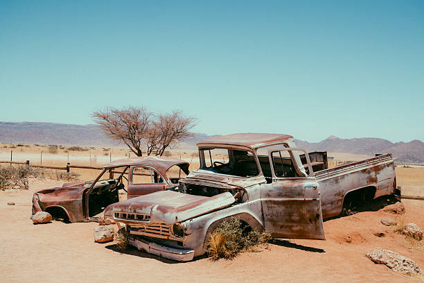Abandoned vintage car wreck sits in a sunbaked Namibian desert near Solitaire. A desolate, timeless landscape with chipped paint and rust evokes nostalgia, loneliness, and rugged travel memories.