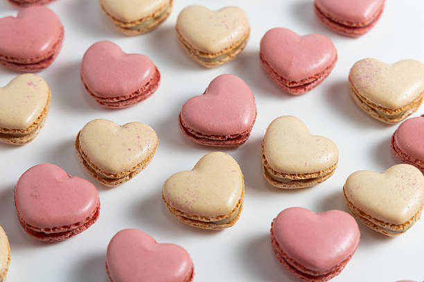 A Delightful Array of Heart-Shaped Macarons Elegantly Arranged on a Pristine White Surface, Showcasing an Inviting Blend of Soft Pink and Beige Hues, Perfect for Creating a Sweet Moment of Joy and Indulgence