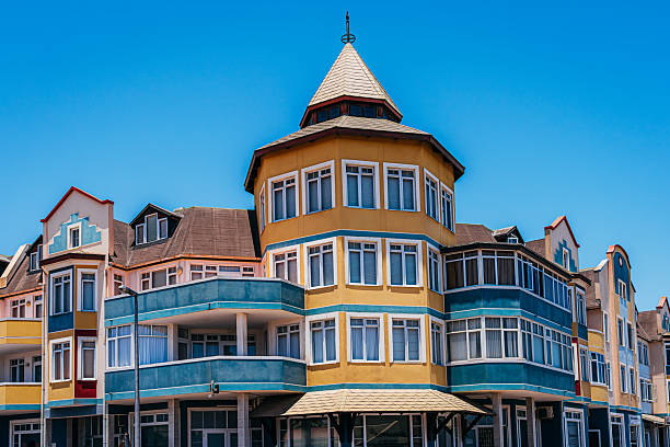 Bright pastel buildings with turrets and balconies line a sunny coastal street in Swakopmund, Namibia, showcasing German colonial architecture and seaside charm for travel and lifestyle imagery.