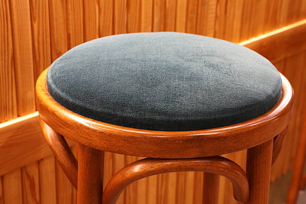 A pair of identical red plastic backless stools are positioned on a light-colored tiled floor near a traditional wooden structure, illuminated by artificial indoor lighting during the evening.