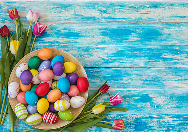 Easter background with painted eggs and colorful tulips, top-down composition