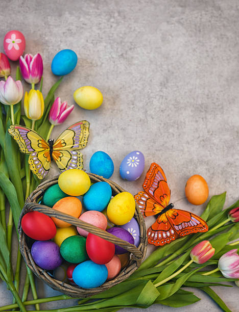 Easter background with painted eggs and colorful tulips, top-down composition