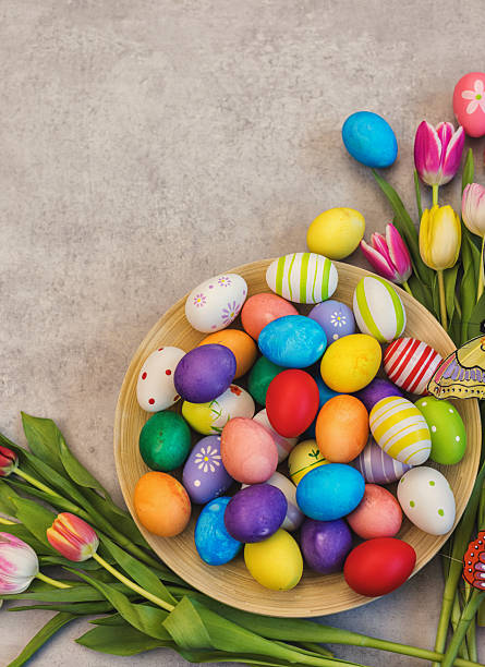 Easter background with painted eggs and colorful tulips, top-down composition