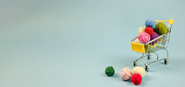 colorful thread in small cart, multicolored fiber displayed creatively in tiny shopping cart visual, vivid assortment of yarn arranged artistically in small shopping cart for social media
