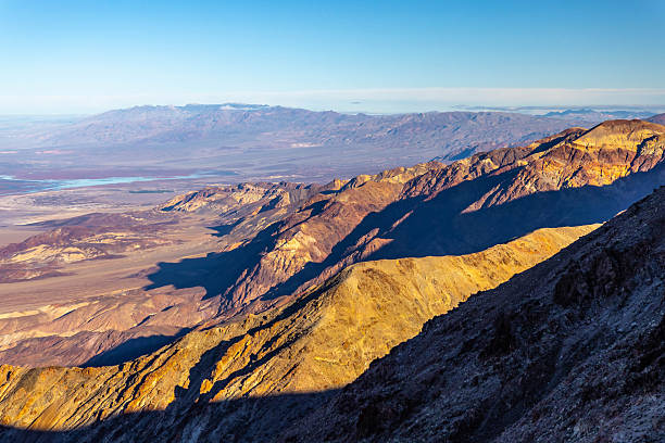 Golden rising sun highlighting mountain peaks at Dante View viewpoint in Death Valley California