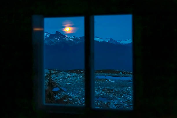 View through Brew hut window to sunset on snowcapped mountain, British Columbia