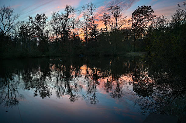 Serene sunset sky reflecting on calm water surrounded by nature