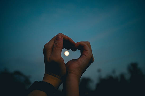 istock Hands forming heart shape framing moon in night sky 2261549707