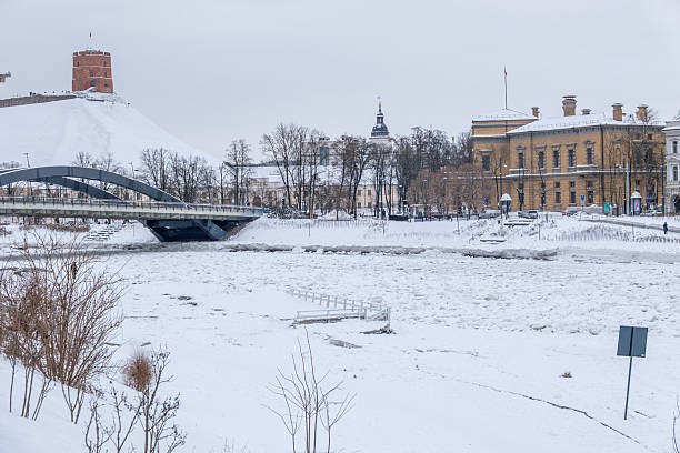 Winter cityscape of Vilnius, Lithuania, featuring the frozen Neris River. Snow-covered ice formations , ideal for climate, winter weather, urban lifestyle, and European city concepts.