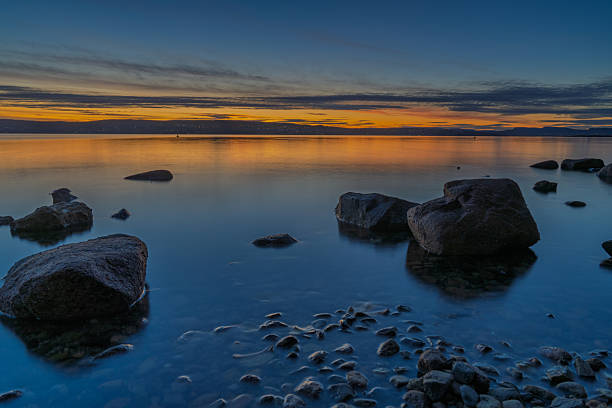 Long exposure at blue hour over Oslofjord near Oslo, Norway. Smooth water, pastel sunset sky and rocky shoreline create peaceful Nordic mood.
