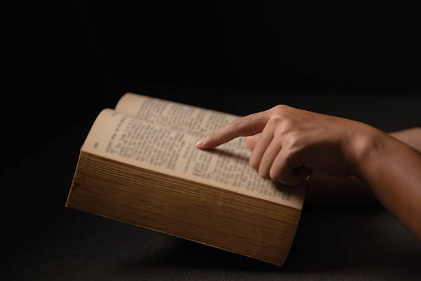 Woman writing notes in notebook at wooden table, close up of hands