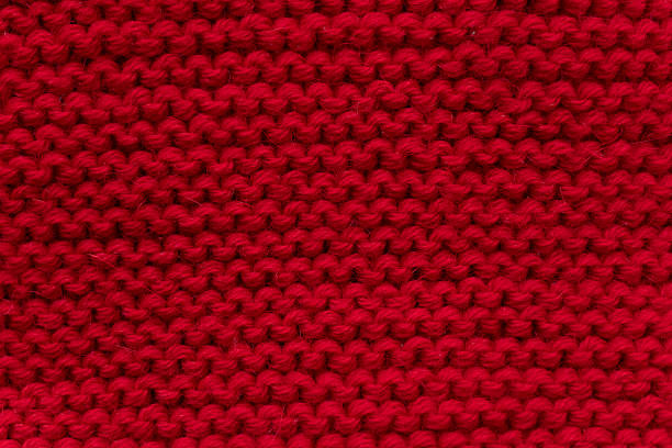 Close-up macro image showcasing a vibrant knitted texture of purple and yellow yarns, highlighting the intricate details of the fibers and their contrasting colors in a soft and cozy composition.