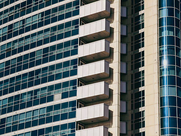 Sleek modern office building facade featuring blue reflective glass, repeating window patterns and vertical fins; conveys corporate, urban architecture and contemporary commercial design with crisp geometric lines.
