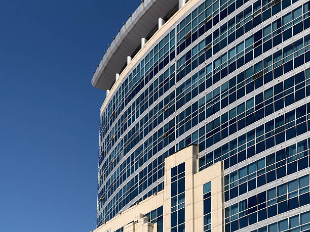 Sleek modern office building facade featuring blue reflective glass, repeating window patterns and vertical fins; conveys corporate, urban architecture and contemporary commercial design with crisp geometric lines.
