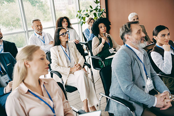 Diverse team of professionals engaged in training and collaborative discussions during a formal business conference in a bright workspace.