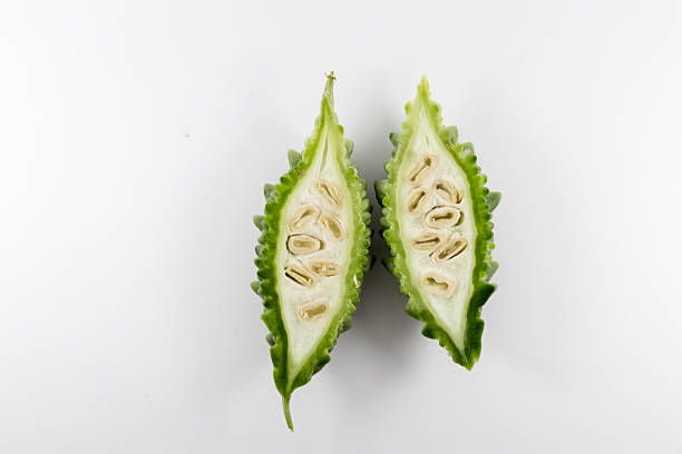 Fresh sliced bitter gourd or karela or bitter melon (Momordica charantia) showing interior seeds and texture, isolated on white background.Ideal for diabetes friendly diets, culinary concept