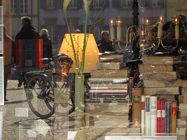 Cozy bookstore window with stacked books, a classic bicycle, and lamp. Reflections of pedestrians in glass blend interior charm with Freiburg street life, DE, 02 Mart 2011