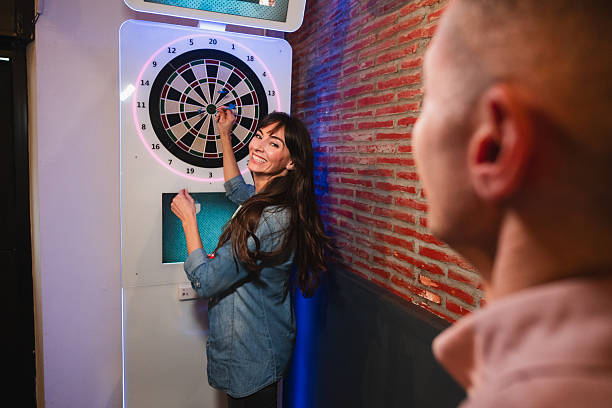 istock Woman smiling playing darts game at a bar 2261649039