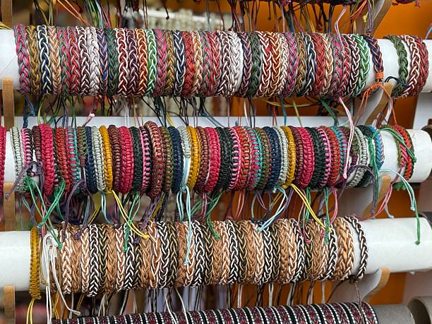 Colorful woven bracelets displayed on multiple rows of a market stall as a creative background. Mobile photo