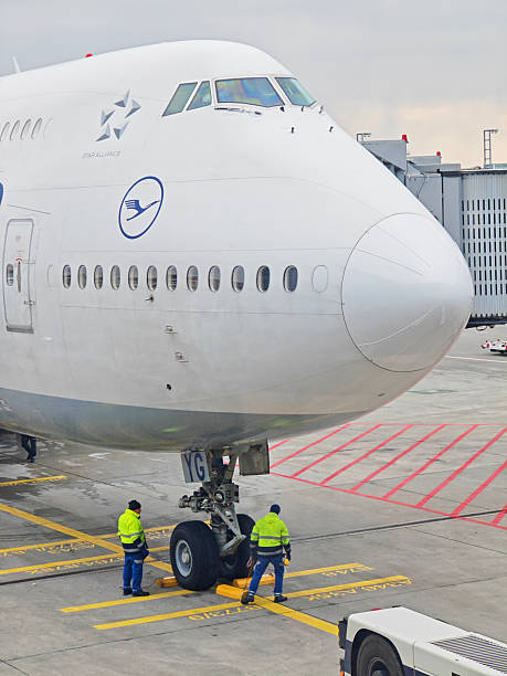Frankfurt, Germany - February 14, 2025: ground staff seen operating on the landing gear on a Lufthansa Group Boeing 747-8 docked to a passenger boarding bridge at Frankfurt Airport.