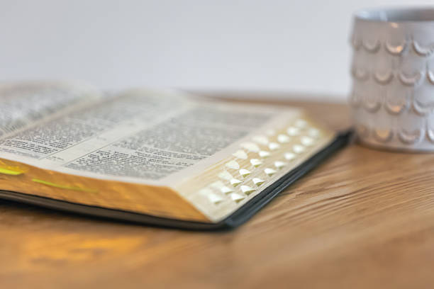 Close view of Bible pages with tabs on a wooden table in soft daylight and gentle bokeh. A home devotional moment for reflection, reset, and quiet wellbeing.