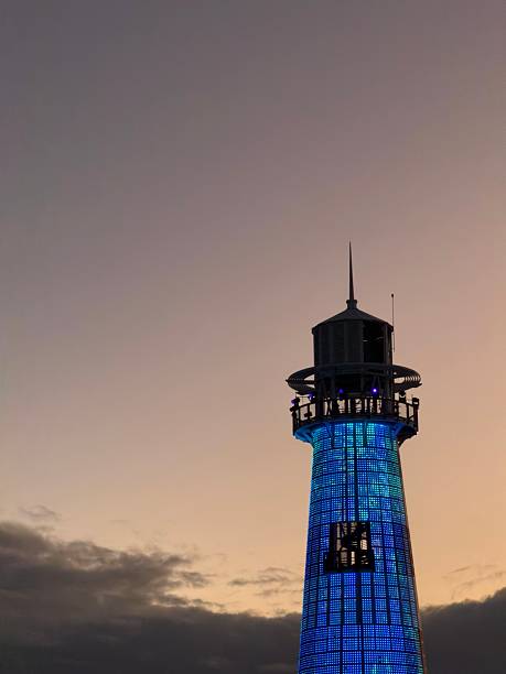 Ocean Cay Lighthouse illuminating the dusk sky with vibrant blue lights against a soft orange and purple background, capturing the essence of an island evening.