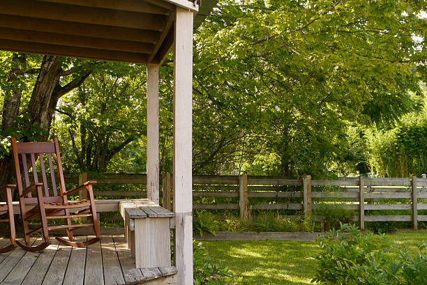 Rural porch in North Carolina with refrigerator and fan sitting on it.